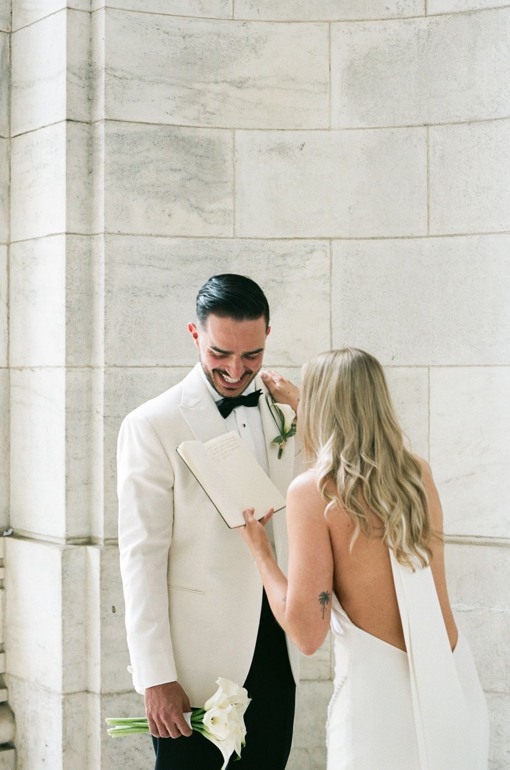 Elegant couple shares an intimate and emotional wedding moment in a light-filled venue with white marble walls.