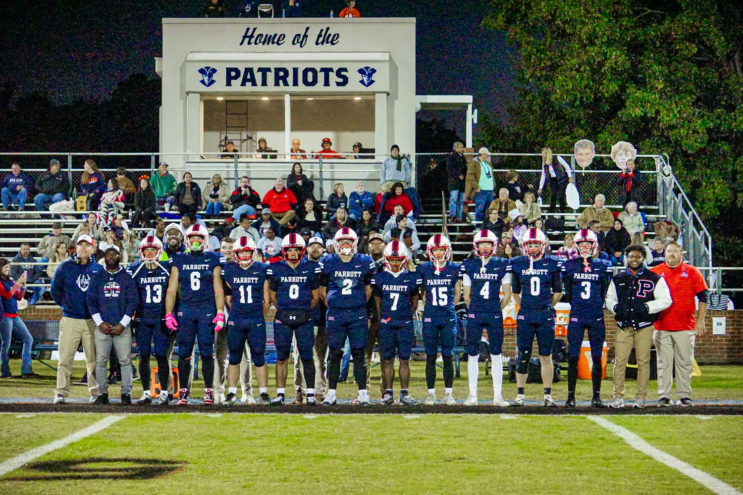 Patriots football team poses together on field during senior night ceremony.