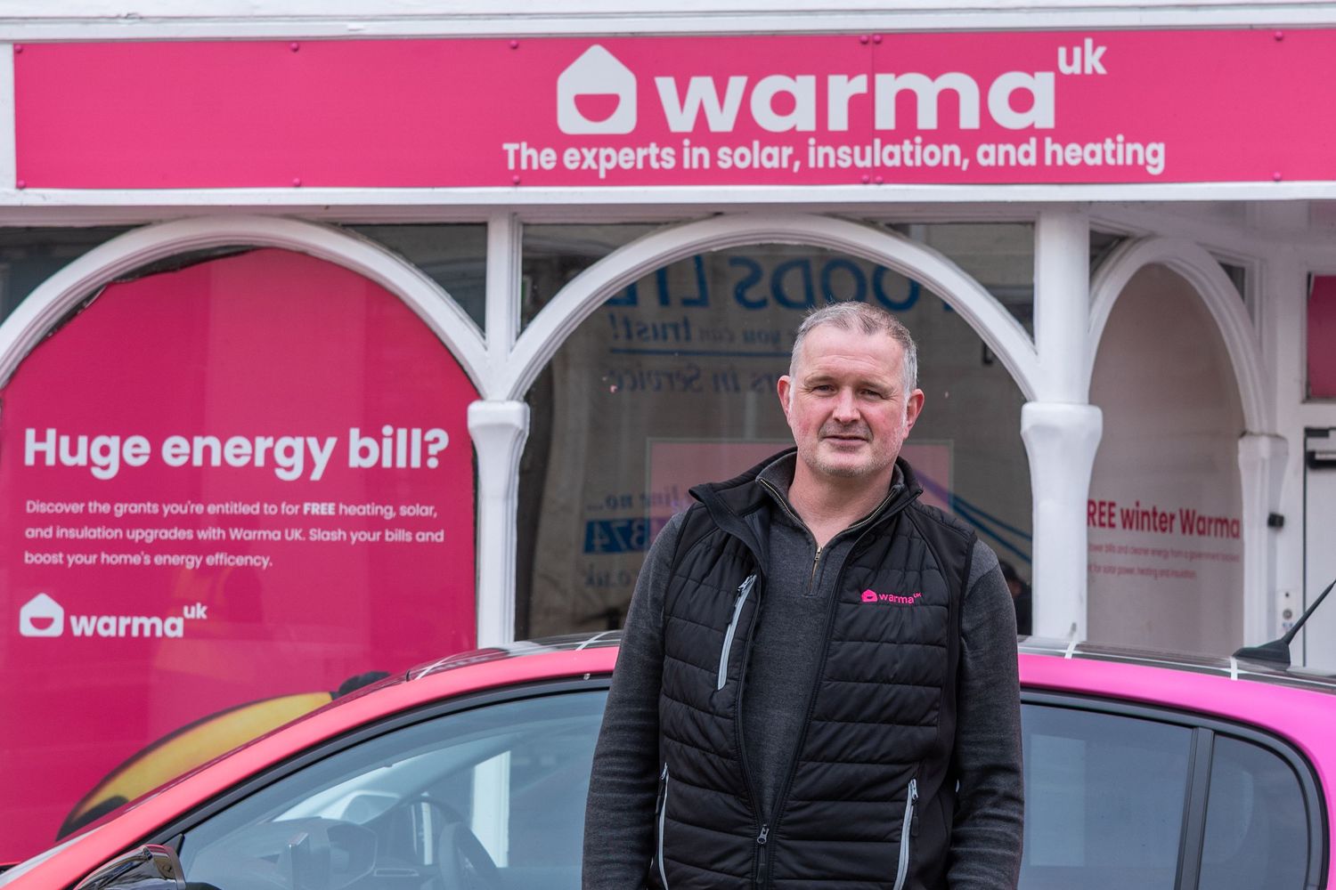 Pink branded company storefront with business signage and staff member visible.