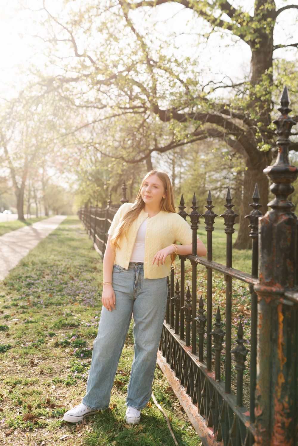 Casual outdoor photos by a decorative iron fence with dappled sunlight filtering through trees.