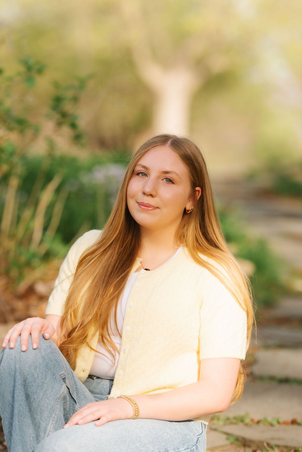 A casual outdoor portrait taken on stone steps surrounded by lush greenery.