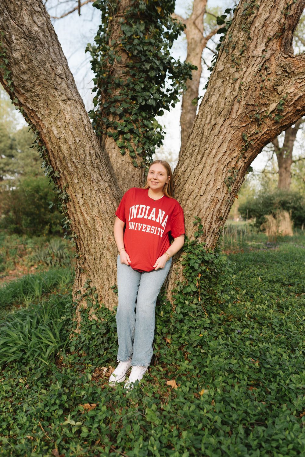 Casual campus photoshoot featuring Indiana University apparel against nature backdrop.