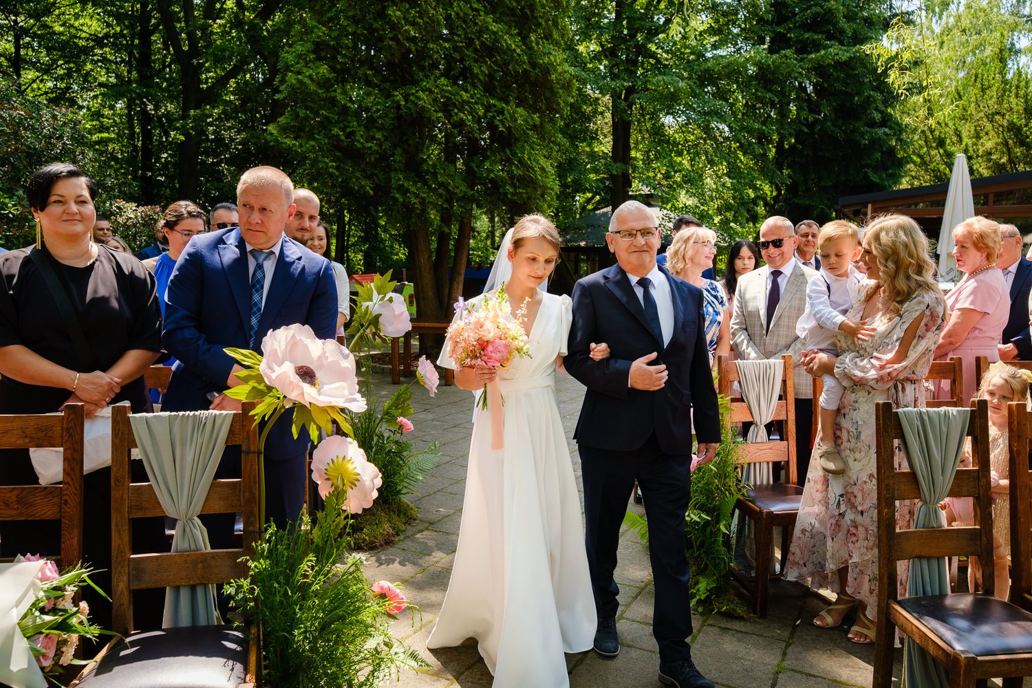 Panna młoda prowadzone przez tatę do ślubnego ołtarza. Ślub cywilny w plenerze.