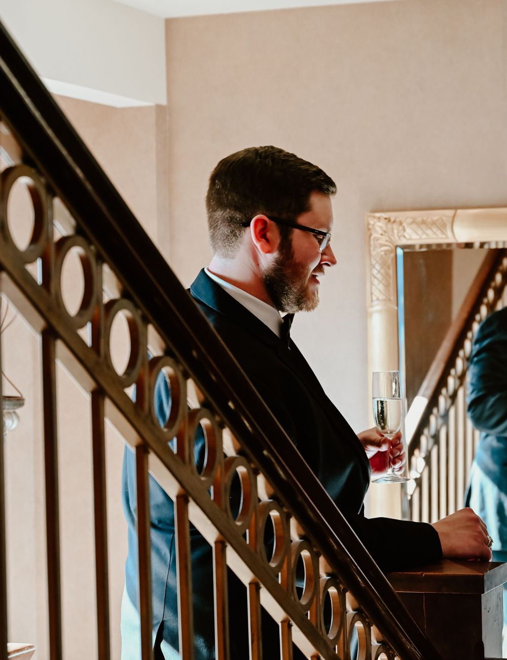 A group of wedding party members in blue get ready while standing along an ornate wooden staircase.