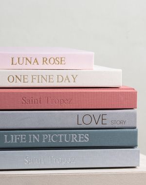 Stack of six pastel-colored books with romantic titles including Luna Rose, One Fine Day, and Love Story arranged on white surface.