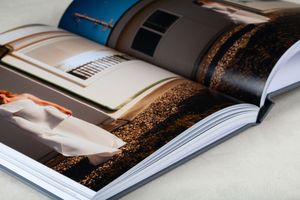 Close-up view of an open hardcover book with glossy pages spread out, showing an artistic coffee bean design layout.