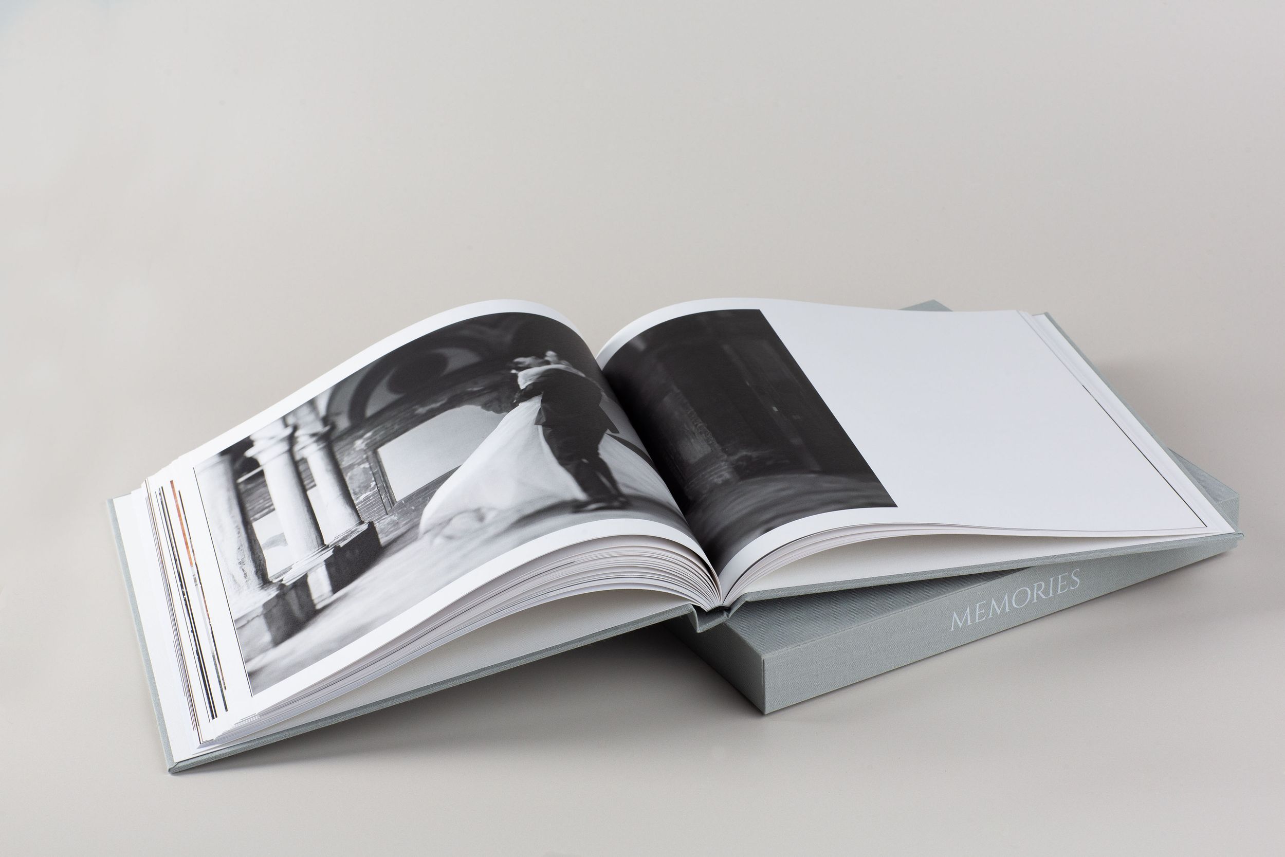 Multiple views of a modern white book with glossy pages showing progressive bending and folding positions.