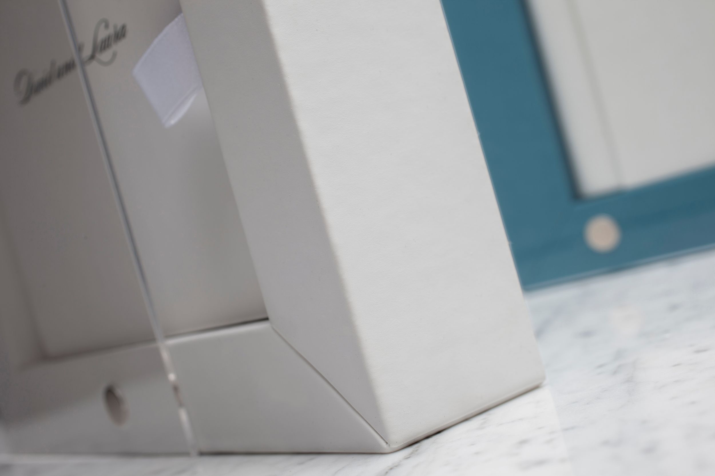 White retail product boxes with turquoise accents arranged in a clean minimalist display.