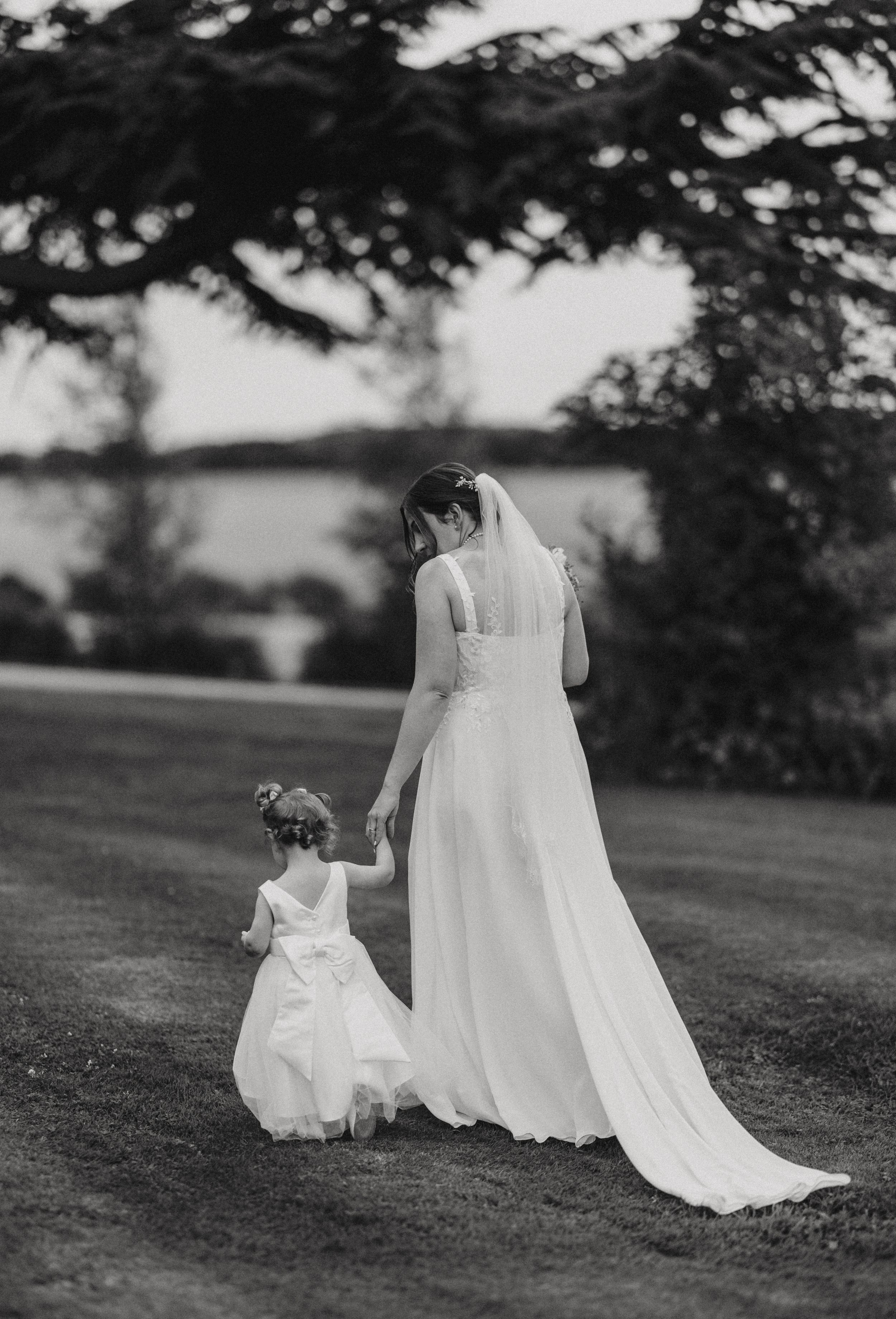 Black and white wedding photo sequence showing a tender moment between figures in flowing white dresses on a grassy hill.
