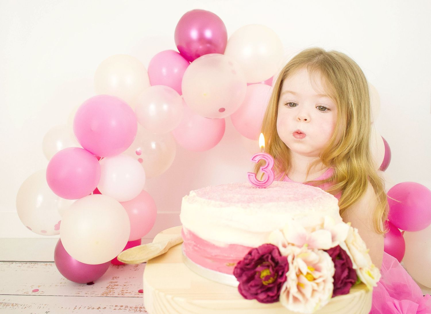 Pink balloons and decorations create dreamy birthday photo backdrop.