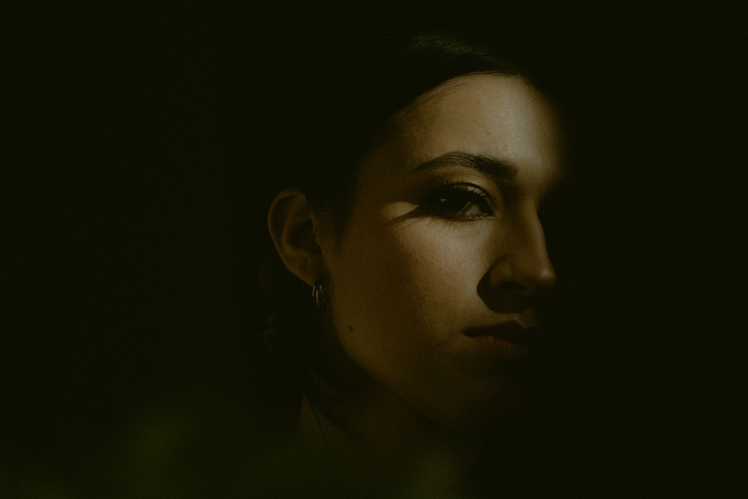 A dark and moody shadowy portrait of a woman.