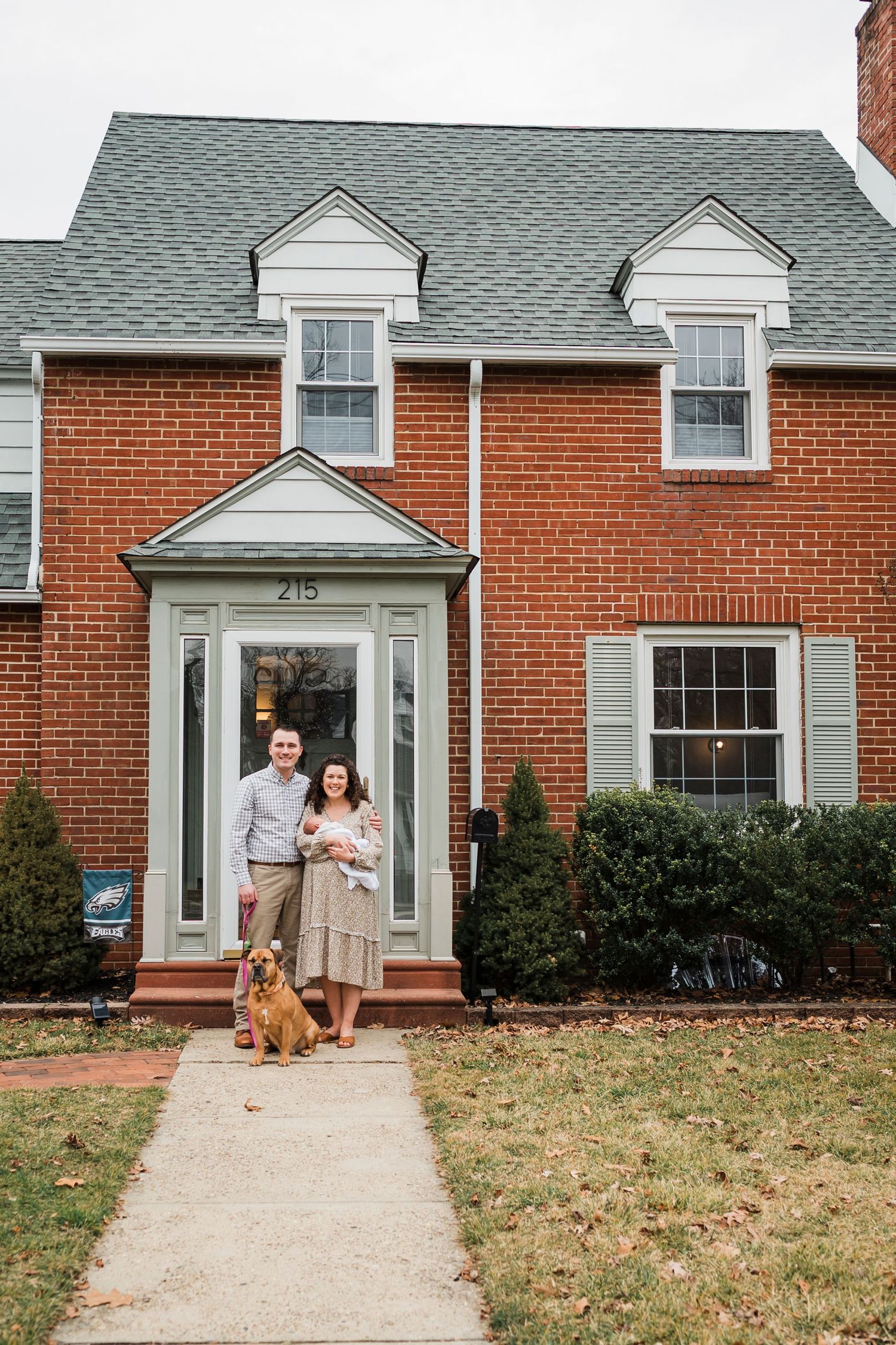 Brick colonial house with white trim and green roof features a classic portico entrance and front walkway.