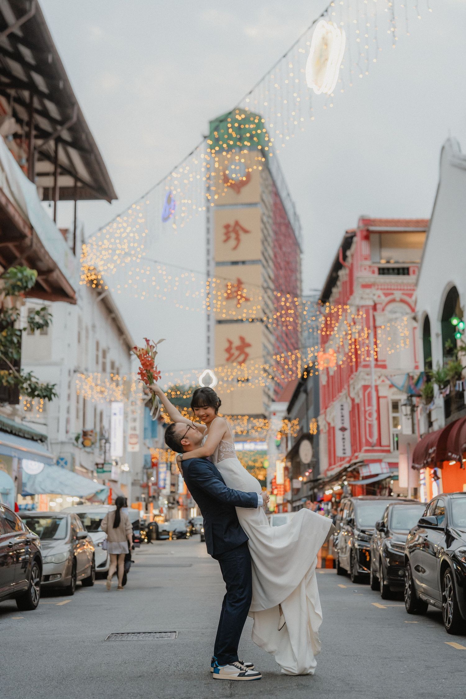 A romantic dance pose in Singapore's Chinatown street decorated with festive lights and traditional lanterns.