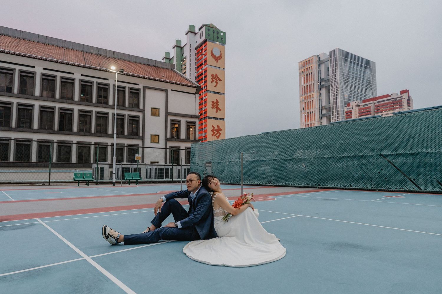 Athletic court on a rooftop with city buildings visible in the background during sunset.