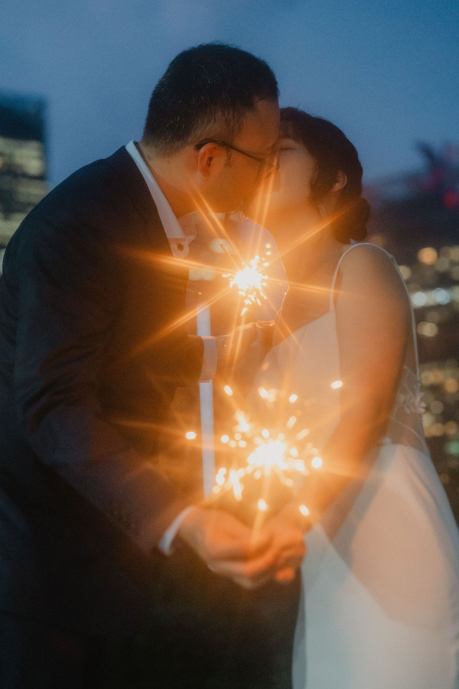 Sparklers create magical light trails and bokeh effects during an evening wedding photoshoot.