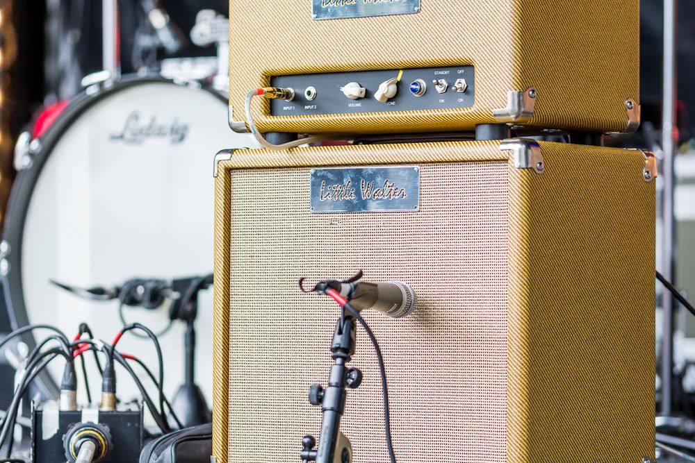 A vintage guitar amplifier stack in mustard yellow with a microphone mounted on the speaker cabinet.