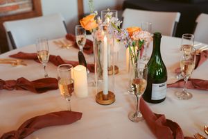 Elegant wedding reception table setting with champagne flutes, candles, and floral centerpieces.
