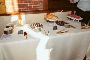A dessert table covered with a white tablecloth displays various pies and sweets on tiered platters at an event.