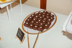 A chocolate-covered wafer bar decorated with chocolate candies lies on a white plate.