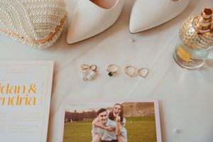 Wedding detail collage featuring rings, invitations, white heels, and rustic decor elements arranged in a soft neutral palette.