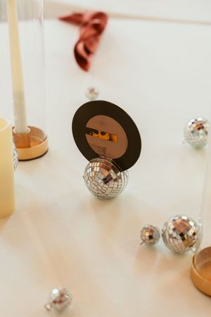 Small disco balls and decorative vinyl record placeholder cards create a retro-themed table setting arrangement.