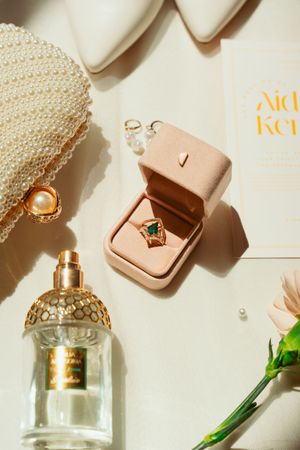 Elegant perfume bottles and delicate jewelry arranged with pearl accessories on a cream-colored background with soft lighting.