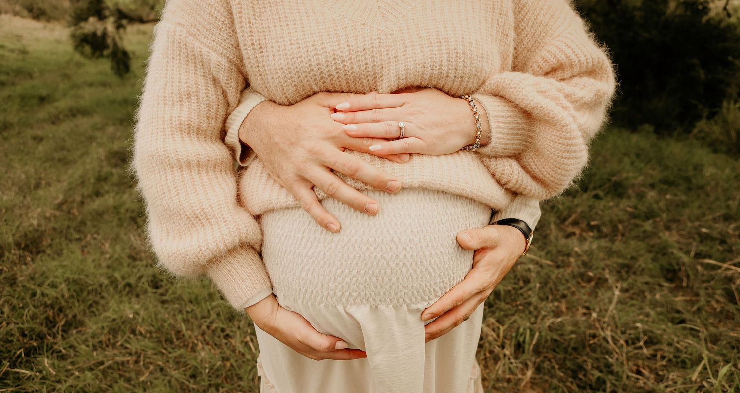 Husband and wife hold maternity belly during photoshoot