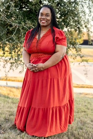 Vibrant red tiered maxi dress with lace trim details and puff sleeves photographed outdoors during golden hour.