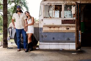 Outdoor vintage bar setting with weathered wood and natural greenery in background.