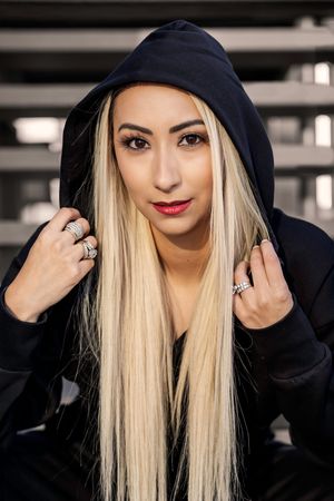 Woman with long blonde hair wearing black hoodie shown in progressive stages of putting hood up over her head.