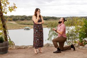 A romantic proposal moment unfolds at a scenic overlook beside a serene lake during autumn.