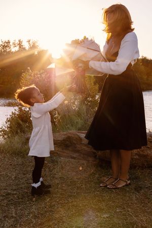 Dancing together at golden hour by the waterfront with sunlight streaming through the trees.