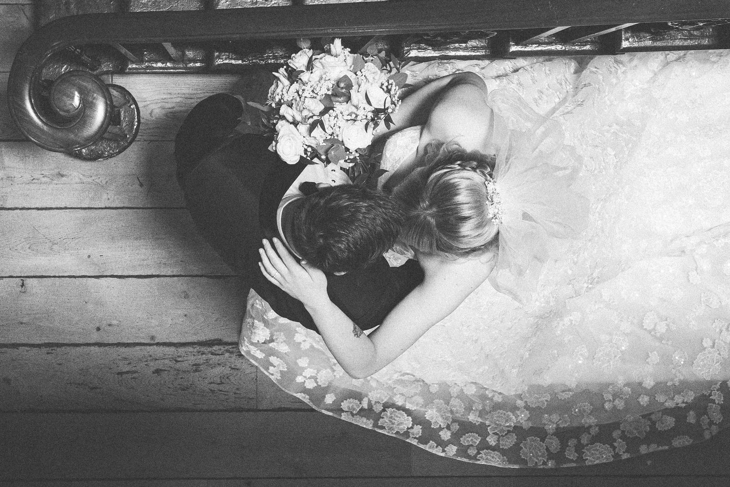 Black and white wedding portrait outdoors against stone wall backdrop.
