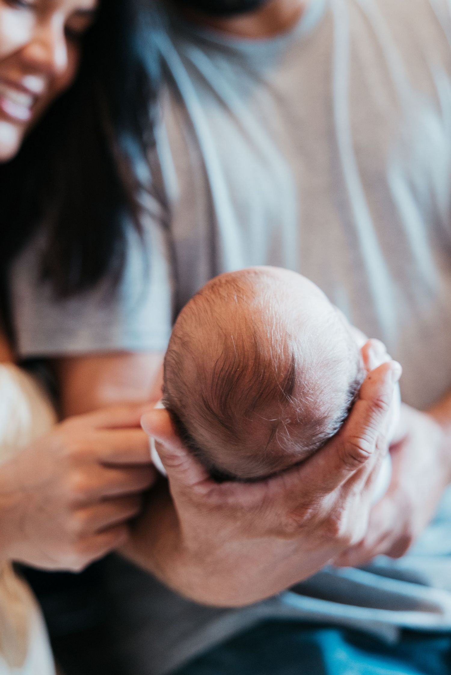 New family cuddling their newborn during in-home lifestyle session in Stuart Florida, newborn photographer in home session, treasure coast