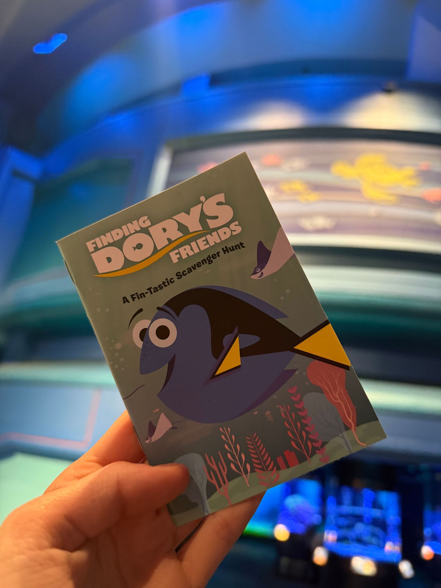 Finding Dory Fastpass ticket held against blue illuminated background.