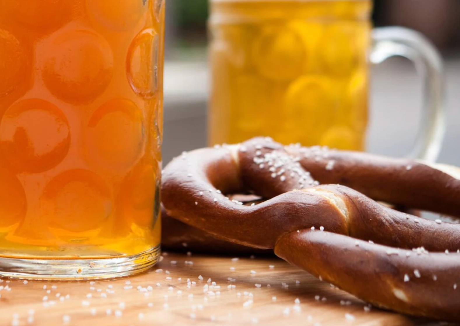 Fresh baked pretzel with beer glasses in soft focus background.
