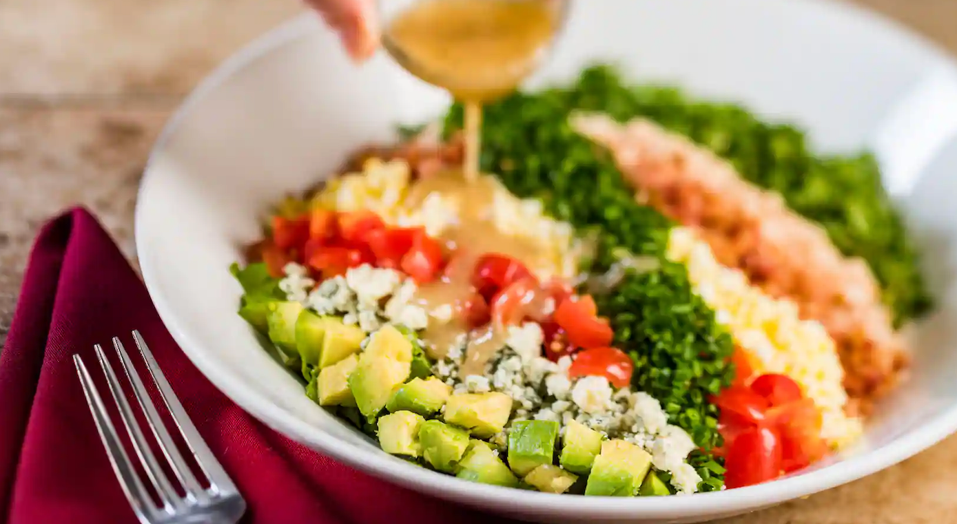 Fresh colorful cobb salad arranged in neat rows with avocado and tomatoes.