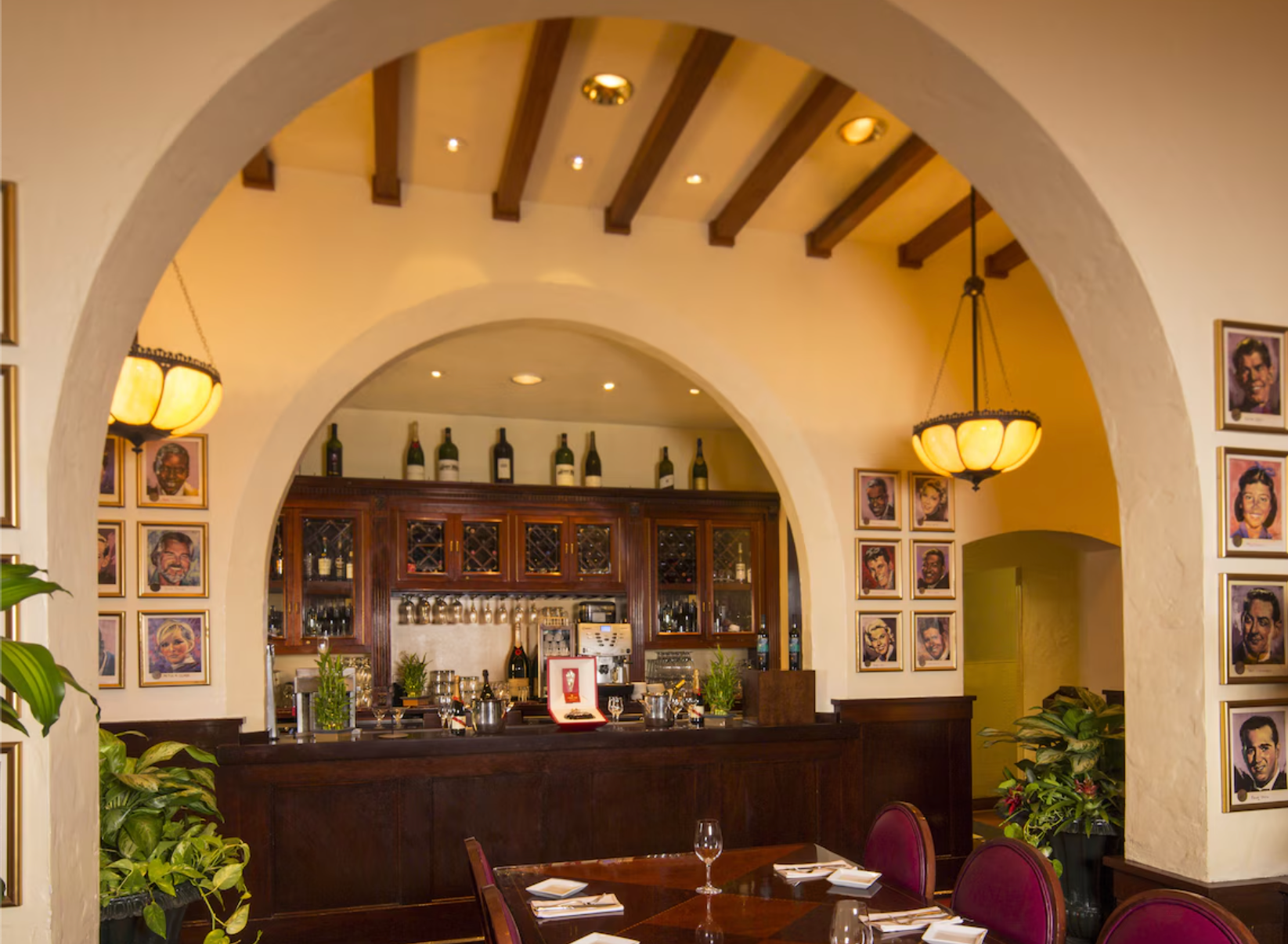 Warm-toned restaurant bar area with Spanish architectural elements and framed photos.