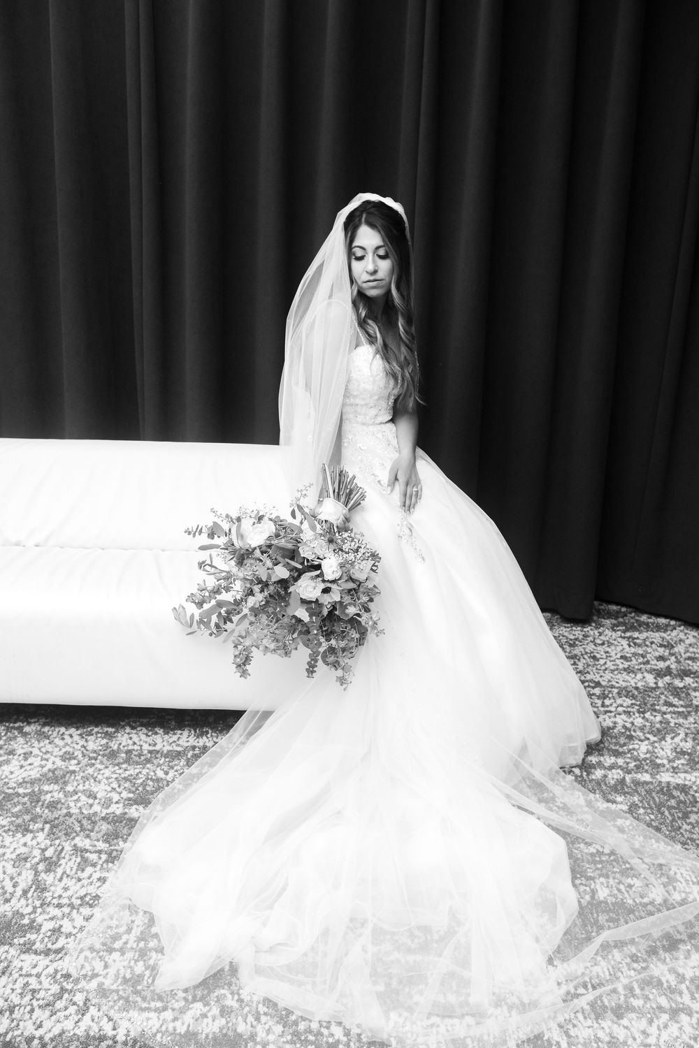A black and white wedding photo series showing an ethereal bride in a flowing veil against a dark backdrop.