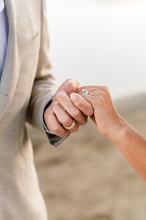 Close-up view of hands exchanging wedding rings during a beach ceremony.