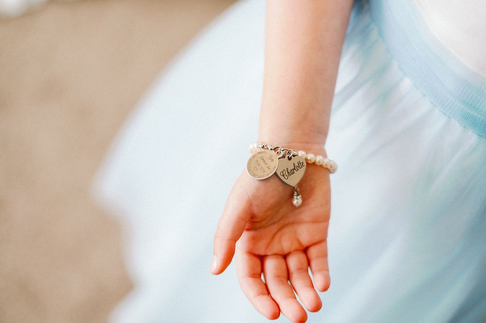 Close-up of hands wearing light blue formal attire with delicate details.