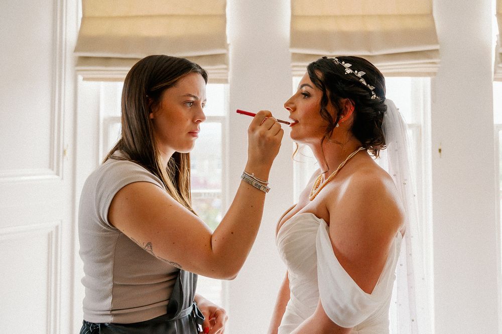 A makeup artist applying final touches during wedding preparations.