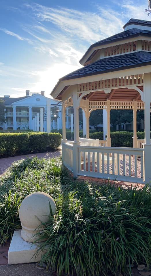 Row of white gazebos with ornate trim surrounded by lush landscaping at a resort.