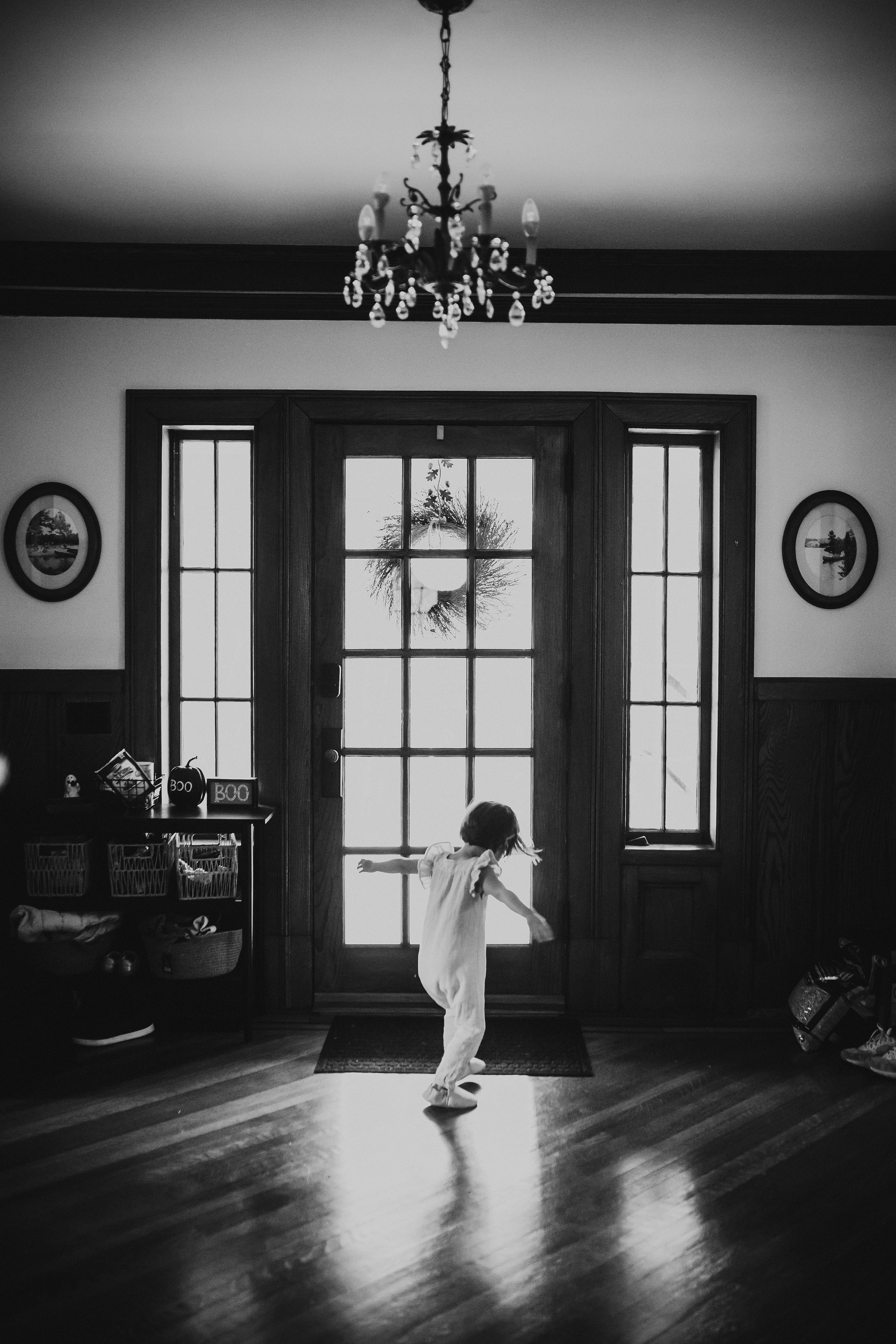 Figure dancing in sunlit room with hardwood floors and large windows.