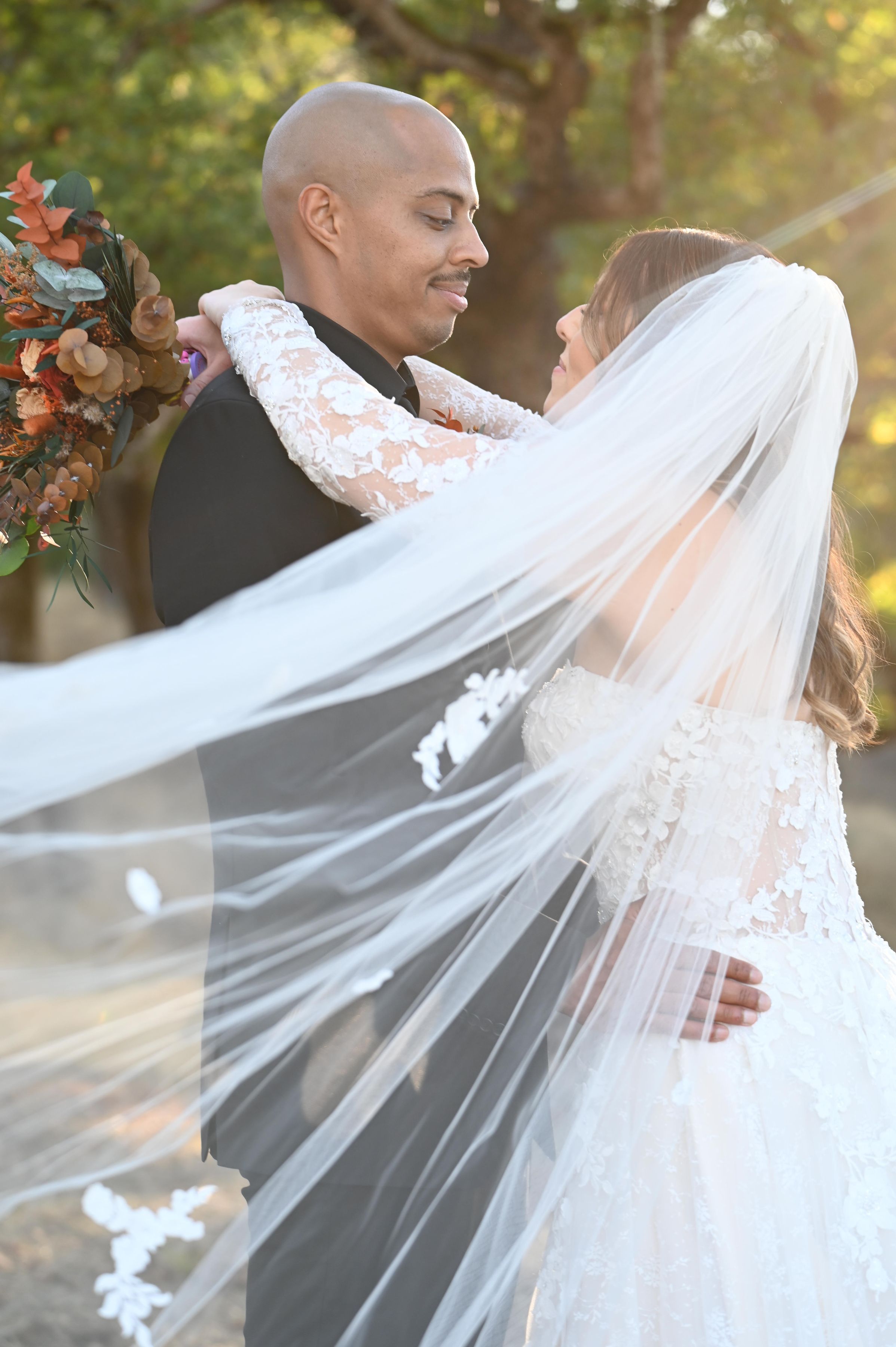 A romantic couple embraces in the evening light while holding a vintage lantern against a soft blue sky and half dome background. Yosemite