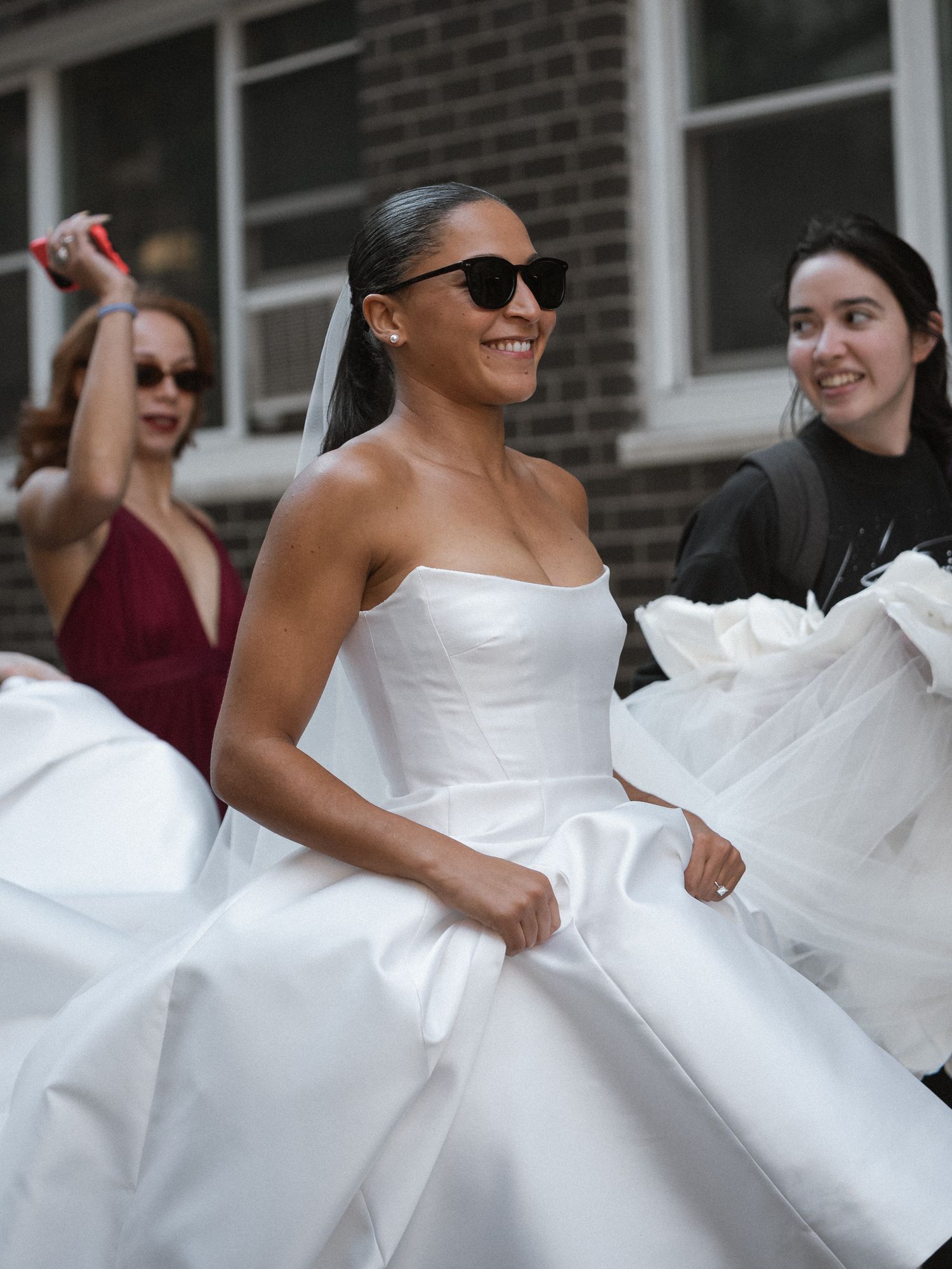 A joyful moment of a bride twirling in her white wedding dress surrounded by friends.