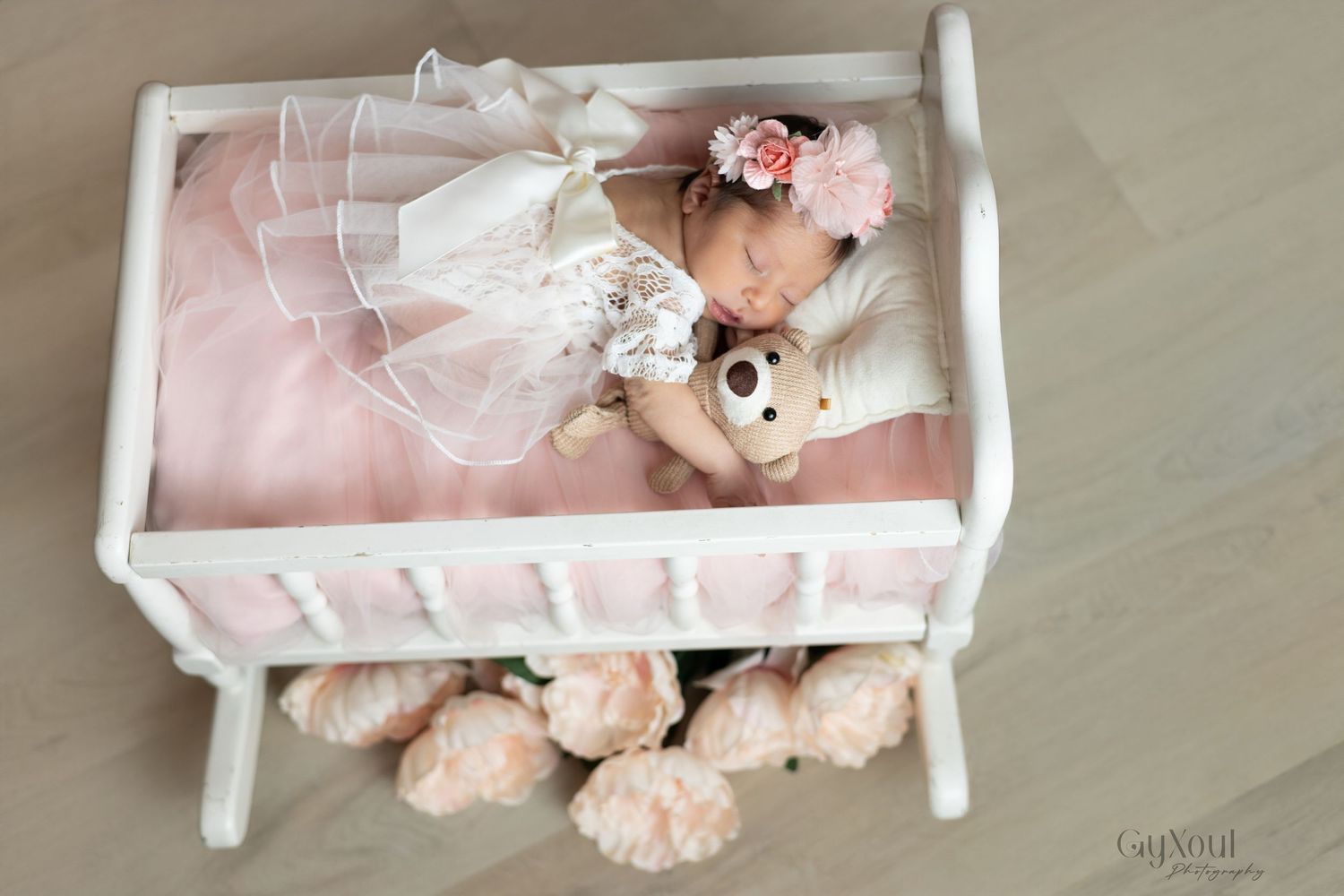 A white wooden doll bed with pink bedding and plush toys arranged neatly on top.