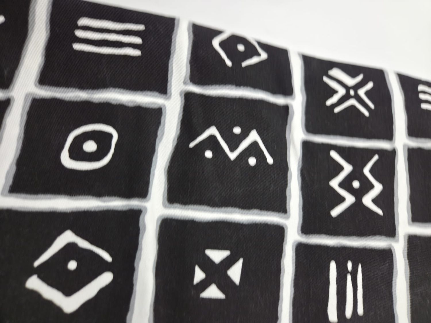 Black and white mudcloth pattern with geometric shapes, lines, and tribal motifs arranged in a horizontal layout.