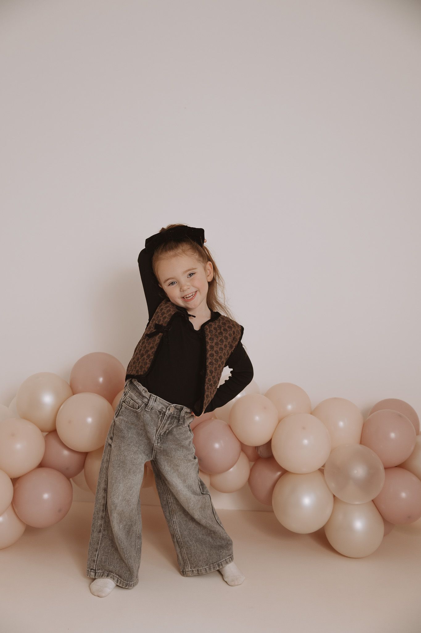 Artistic photo series with pink balloons against neutral wall showing casual poses in denim and black clothing.