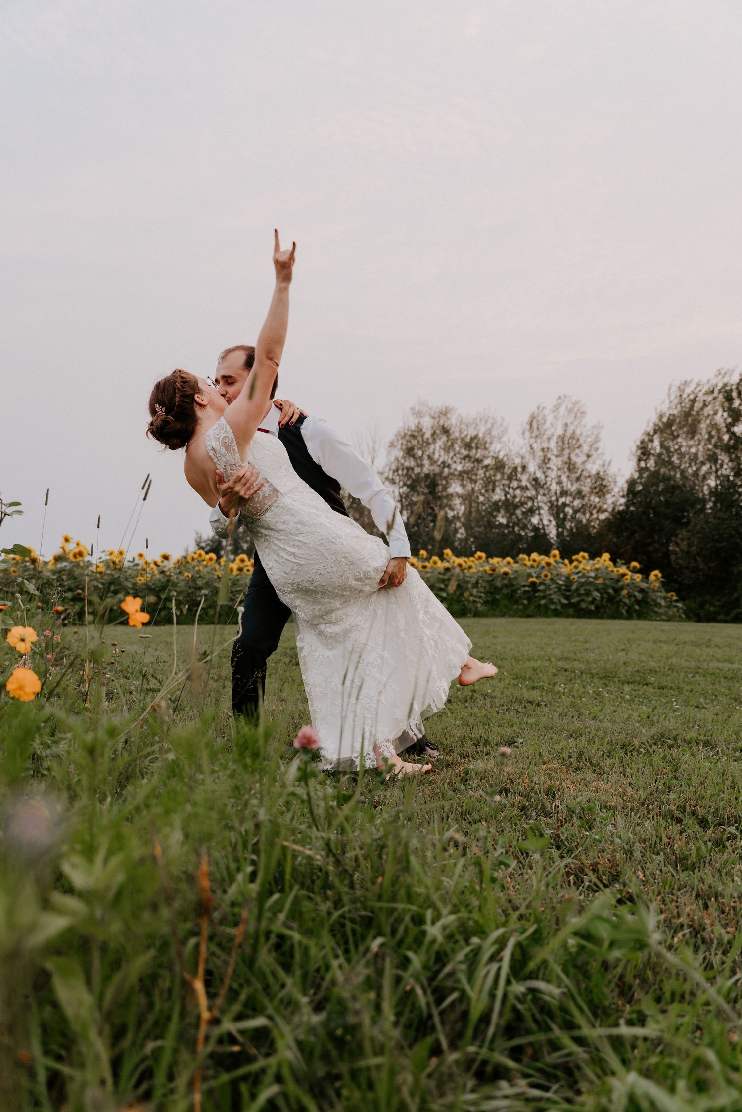 A joyful couple dances and twirls together in a field of wildflowers at sunset.
